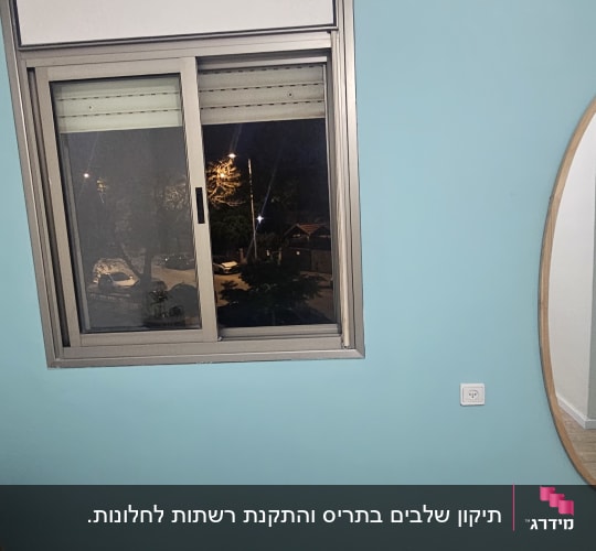חלון עם תריסים בחדר עם קיר כחול